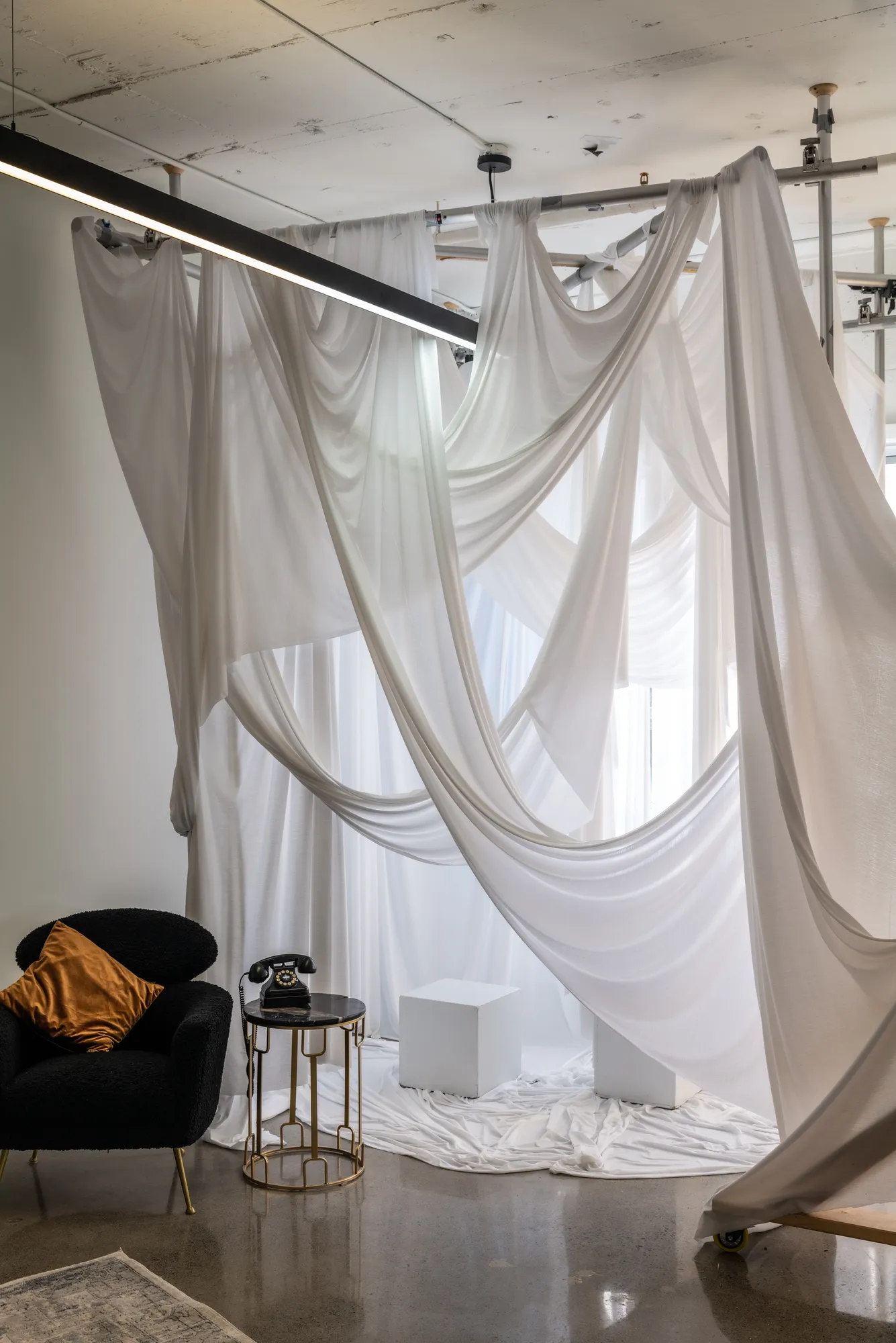 Coin voilage avec drapés blancs et fauteuil noir